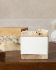 Soap bar with blank label on bath wooden countertop against beige wall close up, mockup