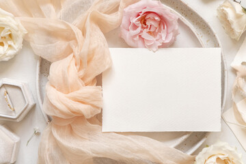 Horizontal Card near cream fabric knot and ring on plates top view copy space, wedding mockup