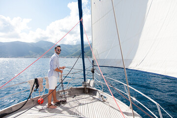 Man sailing on yacht on sea in summer vacation. Traveler enjoying adventure, freedom, wind. Sailor...
