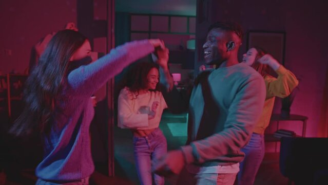 Caucasian woman and black man dancing with friends