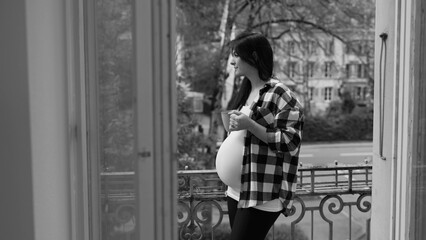 Expectant Mother Relishing Quiet Tea Time on Urban Balcony, Serene Cityscape in Pregnancy's Late Stage in black and white