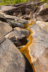 Water trickling down an orange stained granite rock slope that becomes a rock slide in the rainy season for the tourists visiting this popular site in Paluma National Park in Queensland, Australia.