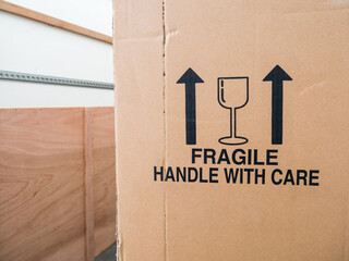A removal van and cardboard box. Box with fragile, handle with care sign and upright container arrows. Concept for moving home, packaging, removals, relocating and storage transportation. Copy space.