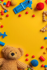 Obraz na płótnie Canvas A yellow background features a frame of colorful toys like a teddy bear, airplane toy, and wooden beads, with room for text.