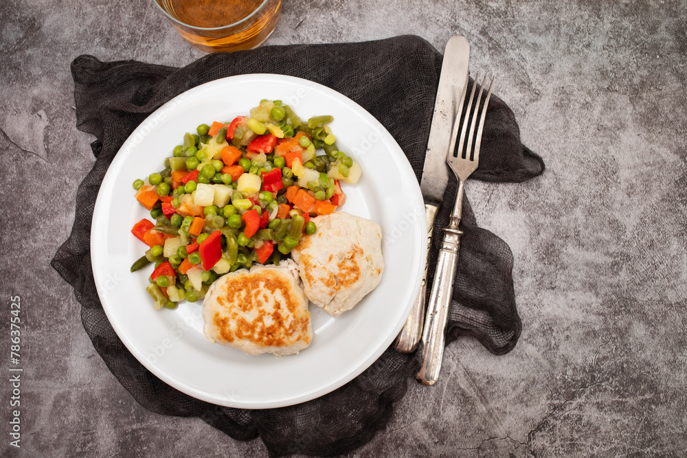 Sticker roasted chicken cutlets with vegetables on white plate