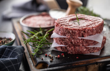 Fresh raw ground beef patties with rosemary salt and pepper made in a meat form on a cutting board - 786375413