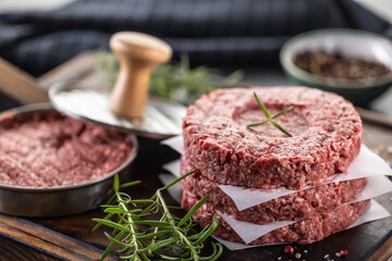 Fresh raw ground beef patties with rosemary salt and pepper made in a meat form on a cutting board - 786375625