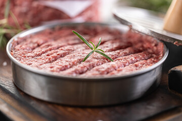 Fresh raw ground beef patties with rosemary salt and pepper made in a meat form on a cutting board - 786375834