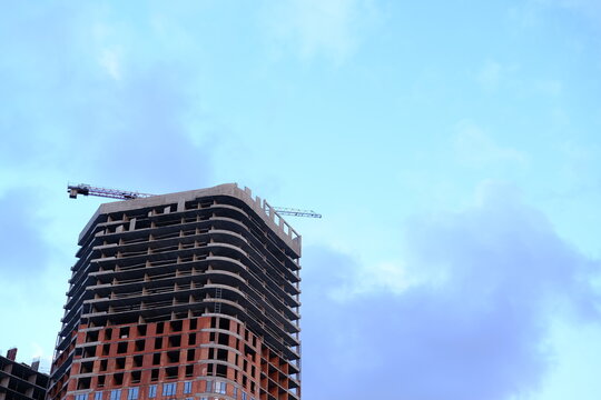 Low angle view of modern office building by construction site against sky in city