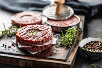 Fresh raw ground beef patties with rosemary salt and pepper made in a meat form on a cutting board - 786376217
