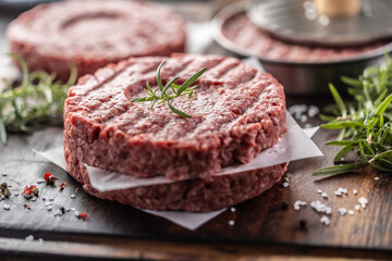 Fresh raw ground beef patties with rosemary salt and pepper made in a meat form on a cutting board - 786376258
