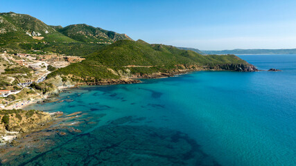Obraz premium Aerial view of Masua beach near Porto Flavia in southern Sardinia, Italy. The sea is crystal clear, clean and with colors ranging from blue to turquoise.