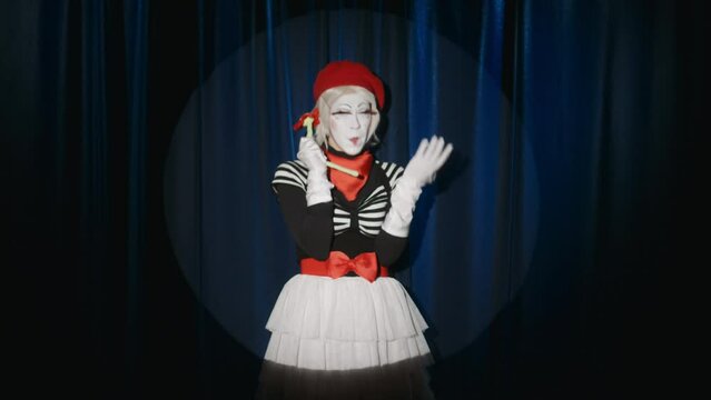 Female mime artist acting like making phone call with flower toy while performing comedy on stage