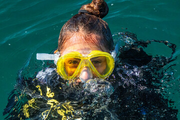 A beautiful red hair latina scuba diver on sea surface after diving underwater