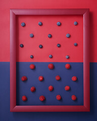 Raspberry and blueberry in frame on red and blue background