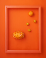 Horned melon, cherry tomatoes, clementine in frame on orange