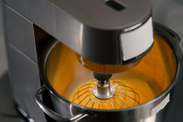 close-up in a professional kitchen machine beats eggs until creamy preparing cream for a cake