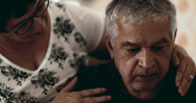 Depressed senior husband in distress while wife tries to give support and help during mental illness crisis, old age despair. Wrinkled 70s caucasian old man