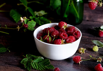 Cup full of fresh ripe garden raspberries against dark rustic background. Shallow DOF with copy...
