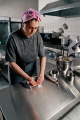 female baker in a professional kitchen wraps the pans with foil before pouring the dough onto the cake