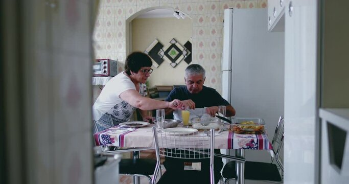 Elderly couple eating lunch during mealtime in authentic depiction of senior spouse and husband at humble home in South America
