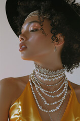 Woman's head in profile. The model wears a mustard yellow silk tank top dress. She has dark curly hair and a black hat made from small white beads and pearls.