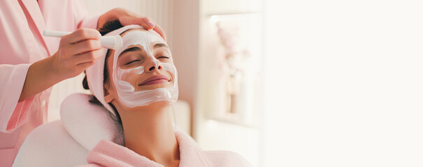 Cosmetology banner. Cosmetologist applying mask on client's face in spa salon. young woman having facial mask spa therapy in beauty salon. beauty therapist applying face mask. Copy space