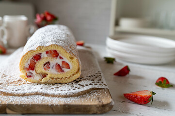 Swiss roll with strawberry cream filling on kitchen counter. Delicious cake roulade