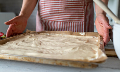 Woman is holding a baking sheet with freshly spread dough in her hands