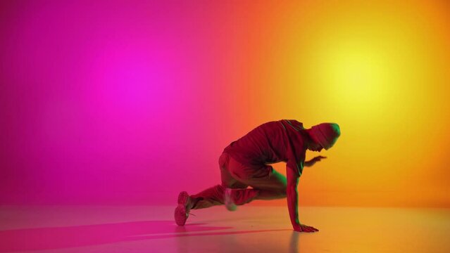 Creative, dynamic video of breakdance performing freezes in neon light against gradient pink-yellow background. Concept of art, hobby, sport, creativity, fashion and style, action. Ad