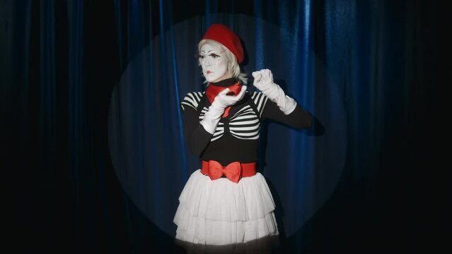 Female mime artist pretending to take picture with camera like photographer during improv comedy show on stage