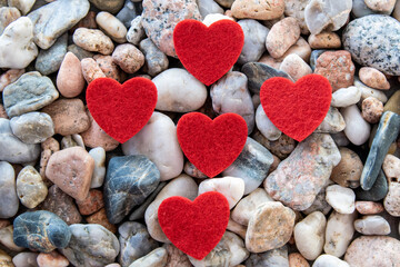 Much red fabric hearts on the river pebble stones.