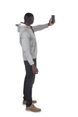 Side rear view of a man taking a self-portrait with his arm raised with a smartphone on white background. - 786402839