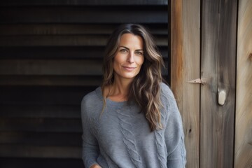 Fototapeta premium Portrait of a tender woman in her 40s wearing a cozy sweater on rustic wooden wall