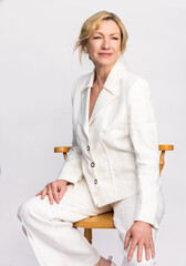 Attractive Smiling Elegant Middle Aged Woman Sitting on Stool in White Suit - 786406233