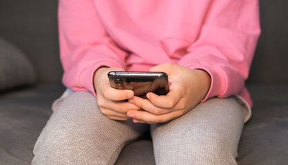 Close-up of children's hands holding, using smartphone. Child plays online games. Internet addiction. Selective focus.