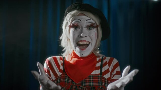 Female mime artist in French outfit looking at camera, portraying excitement and happiness while performing on stage