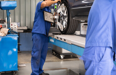 Car repair shop employee adjusting the car's wheel balance.