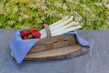 A basket with white asparagus and strawberries.