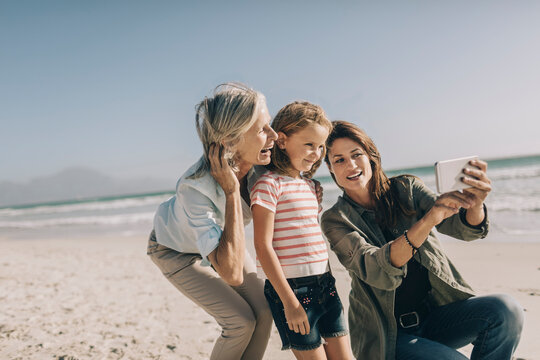 Happy three generation family taking a selfie on a sunny beach