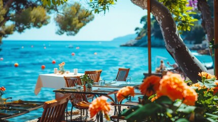 Authentic atmospheric cafe on the shore of the French Riviera under green trees overlooking clear blue water, colorful flowers in the background - obrazy, fototapety, plakaty
