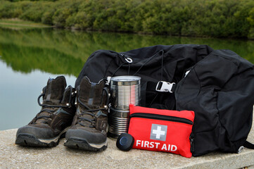 hiking equipment with a backpack, hiking shoes, cans of food, and for safety, a first aid kit and a...