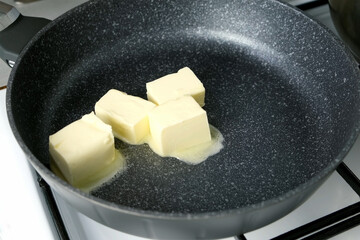 Woman cooking melting butter on frying pan mixing with wooden spatula. Heating butter cubes preparing dish. Cuisine culinary prepare cook dish domestic food recipe ingredients. Healthy nutrition.
