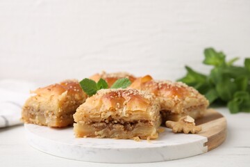 Eastern sweets. Pieces of tasty baklava on white wooden table, closeup