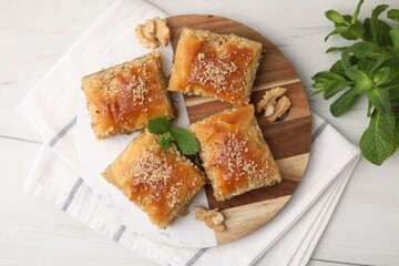 Eastern sweets. Pieces of tasty baklava on white wooden table, top view