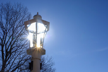 the light post has a cross on it and the sun shines in the background