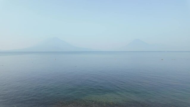 Water taxi moving across lake Atitlan in Guatemala in front of volcanos panorama 