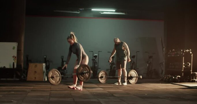 Athletes doing clean and jerk weightlifting exercise in gym