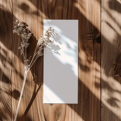 Dried flowers and blank paper on wooden background.