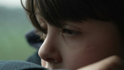 Pensive child close-up eyes and face while traveling by train with contemplative gaze. Thoughtful...